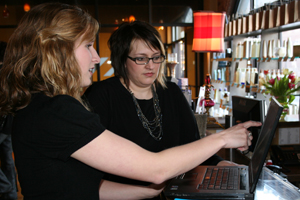 Alumna Kathleen Mills ’10, left, consults with Sonia Stancombe, owner of Nicholas J Salon and Spa in South Bend. Kathleen recently made a breakthrough for the business when she figured out how to get the business’s sales program to communicate with the ac